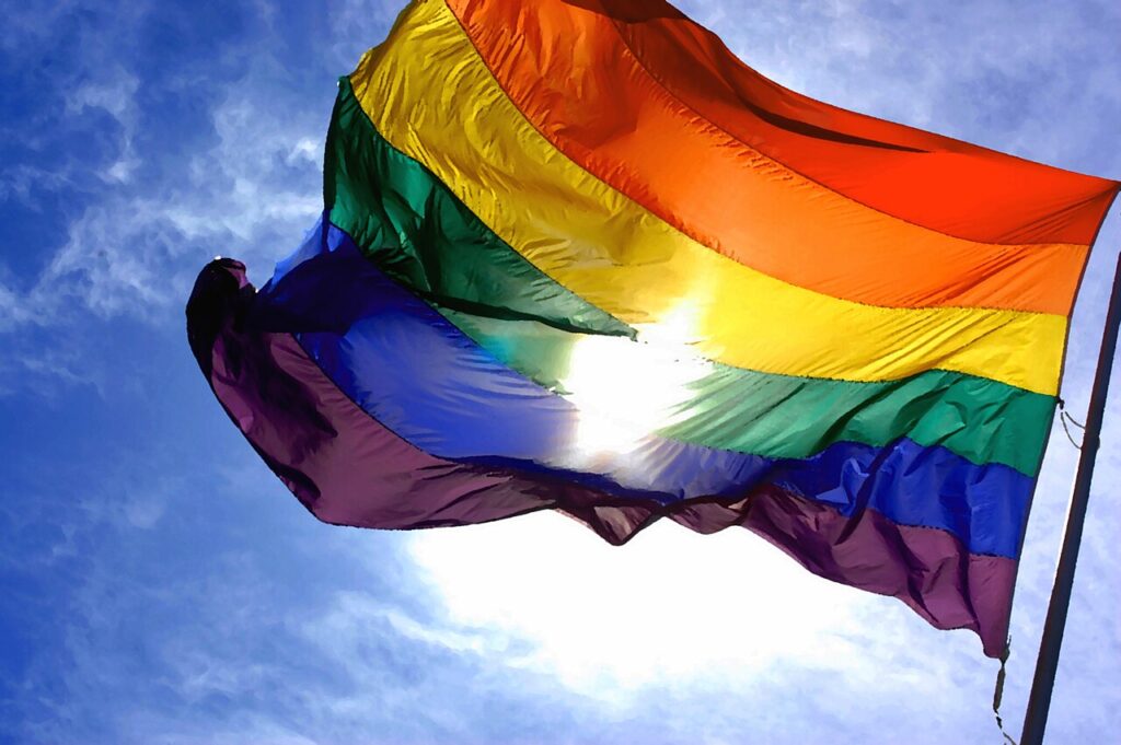 Autor Rainbow_flag_and_blue_skies.jpg: Ludovic Bertron from New York City, Usaderivative work: Marlith (talk) - Rainbow_flag_and_blue_skies.jpg, CC BY-SA 3.0, https://commons.wikimedia.org/w/index.php?curid=6209832